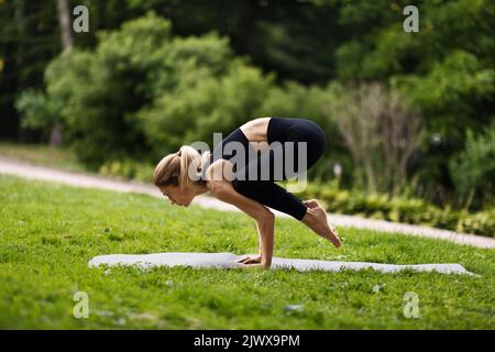 Side view of athletic woman standing in crow pose Stock Photo