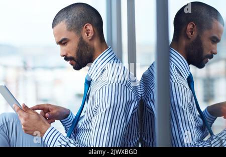 Installing a new corporate app. a young businessman using a digital tablet outside of an office building. Stock Photo