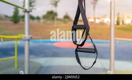 Great TRX workout fitness to exercises outdoors. A special hanging device for exercising outside in sunny city park. Healthy lifestyle concept. Stock Photo