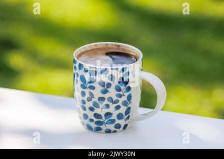 cup of coffee on white table in the garden, selective focus Stock Photo