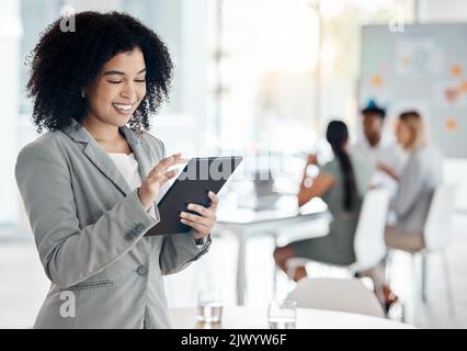 Business woman working on a digital tablet doing research while in a team meeting in the office. Corporate employee reading information on the company Stock Photo