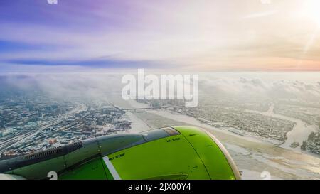 Surrealistic aerial sunset from a airplane window with green engine over a city Stock Photo