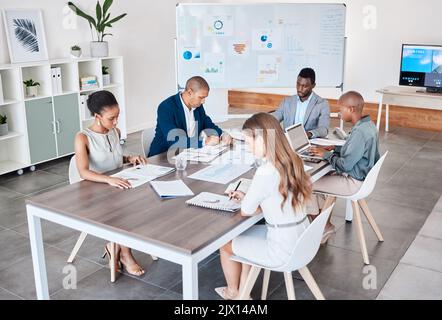 Business people working on documents and laptop at a office boardroom table. Group of professional, diversity and analysts browsing ideas online and Stock Photo