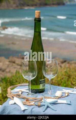 Tasting of txakoli or chacolí slightly sparkling very dry white wine produced in Spanish Basque Country, served outdoor with view on Bay of Biscay, At Stock Photo