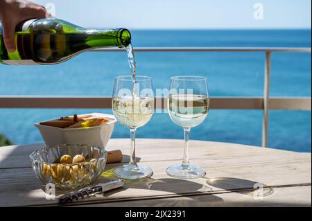 Pouring of txakoli or chacolí slightly sparkling very dry white wine produced in Spanish Basque Country, served outdoor with view on Bay of Biscay, At Stock Photo