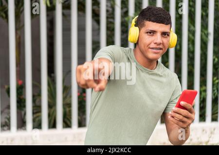 Man In Headphones Using Mobile Phone At City Street Stock Photo