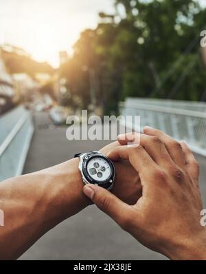 Making progress on the road to fitness. a runner checking his sports watch while training. Stock Photo