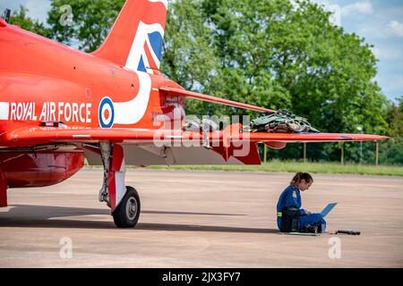 Member of the Royal Air Force aerobatic team, known as the Red Arrows, working on a laptop at RAF Fairford, England. The Red Arrows pilot the BAE Systems Hawk T1 aircraft, a two seater plane used for pilot training. The Hawk T1 can reach a top speed of 1037 km/h. It is powered by a single Rolls-Royce Turbomeca Adour Mk 861 turbofan. Photographed on the 2nd of June 2022. Stock Photo