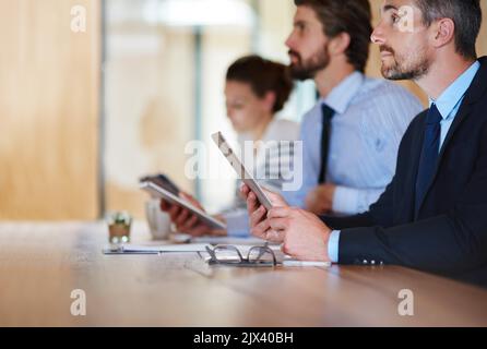 Learning new ways to do business. businesspeople using their digital tablets during a conference. Stock Photo