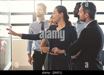 Strategy is this teams strength. young businesspeople discussing ideas on a whiteboard during a meeting in an office. Stock Photo