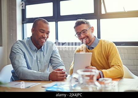 Technology makes working together easy. two designers working on a digital tablet in an office. Stock Photo