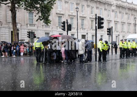 London, UK, 6th September, 2022. Reporters and members of the public wait in the torrential rain lashing down in Whitehall. Liz Truss is delayed arriving to deliver her first speech as Prime Minister in Downing Street because of the rain. Following the result of the Conservative Party members' vote, Liz Truss travelled to Balmoral to meet the Queen and was invited by her to form a government. Credit: Eleventh Hour Photgraphy/Alamy Live News Stock Photo