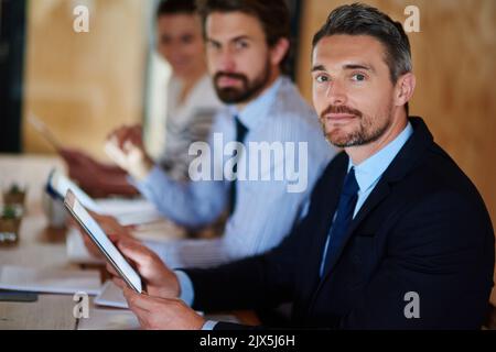 Keeping our skills up to date. Portrait of a businessman using a digital tablet during a conference. Stock Photo