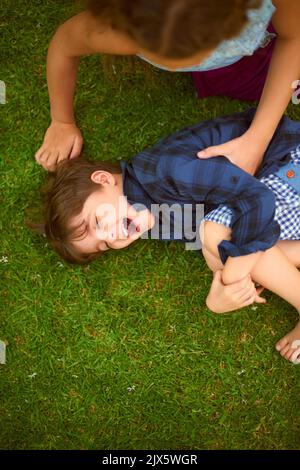 Nothing but tickles and giggles when theyre together. High angle shot of a young girl tickling her brother while playing outside on the lawn. Stock Photo