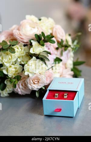 A pair of beautiful wedding rings and a delicate bridal bouquet of roses. Wedding ceremony. Soft selective focus. Stock Photo