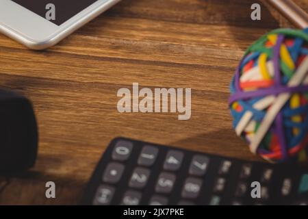 Close-up of rubber band ball with calculator on wooden table Stock Photo