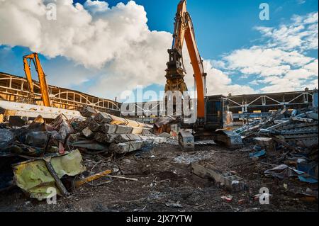 Excavator with hydraulic scissors cuts concrete beams Stock Photo