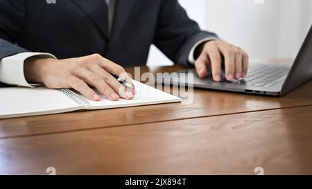 cropped and close-up, Successful and smart Asian businessman in formal suit working at his desk, using laptop computer. Stock Photo