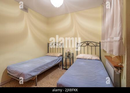 Two beds in a small simple bedroom in a hostel, motel or guest house. Concept of budget accommodation for rent or travel Stock Photo