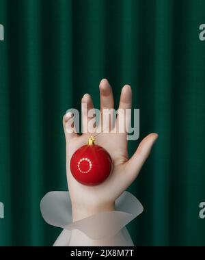 Happy New Year 2023. Red Christmas decoration ball hang on hand against background of green curtain. Festive realistic decoration. Holiday greeting ca Stock Photo