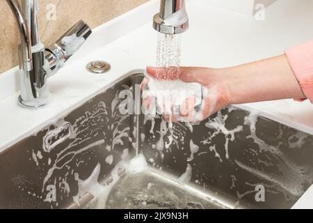 Sponge in a woman's hand is washed off with tap water Stock Photo