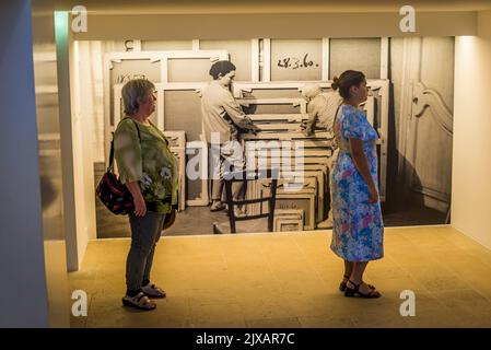 Two women looking at a Picasso painting and a photograph of him and wife   labelling paintings in the background, Picasso Museum, an art gallery located in the Hôtel Salé in rue de Thorigny, Paris, France Stock Photo
