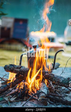 Preparing coffee or tea on a bonfire with branches and flames outdoor in the nature, vertical Stock Photo