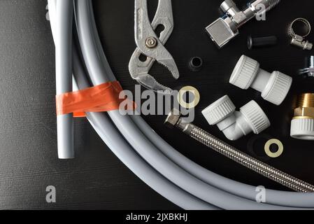 Detail of group of plumbing materials and tools on black table. Top view. Horizontal composition. Stock Photo