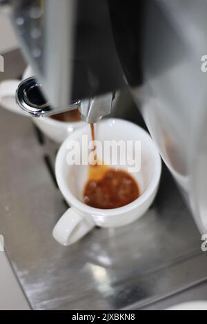 Aromatic Espresso Dripping into Two White Cups. Espresso Machine Coffee Making. Stock Photo