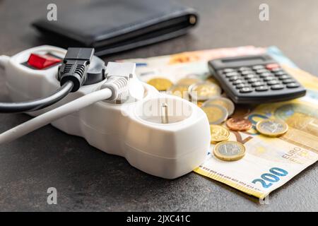 Electric plug, euro money and calculator on the black table. Concept of increasing electric prices. Stock Photo