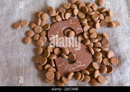 Dutch Sinterklaas tradition: A chocolate letter and candy called Pepernoten on a jute background. Stock Photo