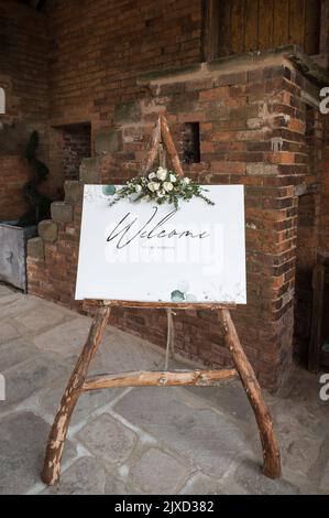 Welcome sign to wedding, wooden frame natural wood with flowers bouquet floral display.  Standing outside wedding venue to welcome guests. Stock Photo