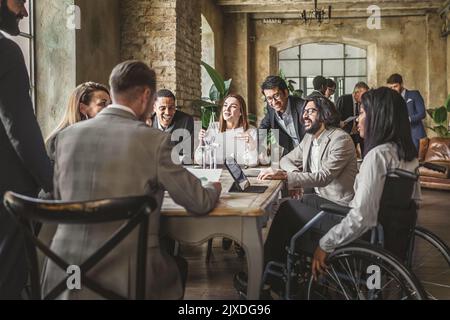 Multiracial group professional business workers in suit with people with disabilities on the wheel chair discussing sitting around the meeting table o Stock Photo