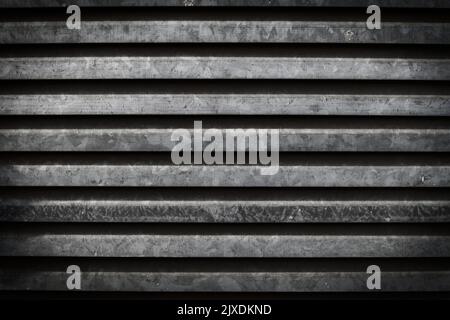 Close-up of a kind of metal shutter that offers a texture of horizontal lines and gray and black colors with a grunge weathered surface. Stock Photo