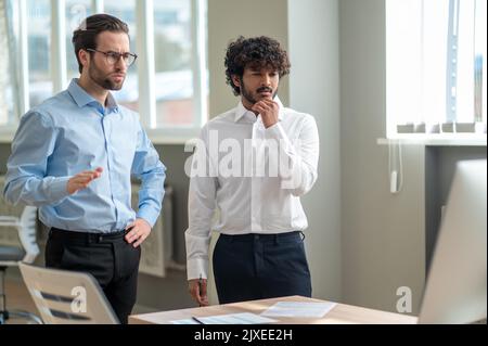 Work on project. Two businessmen looking busy while discussing project in the office Stock Photo