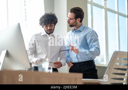 Work on project. Two businessmen looking busy while discussing project in the office Stock Photo