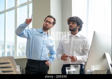 Work on project. Two businessmen looking busy while discussing project in the office Stock Photo