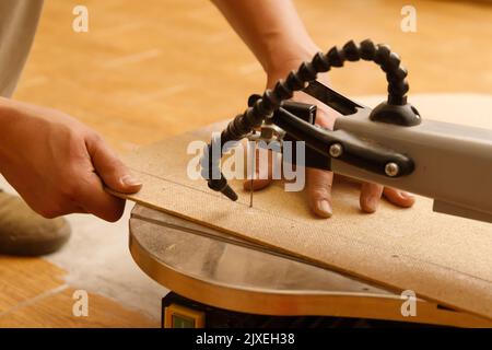 Carpenter's hands are working on scroll saw Stock Photo