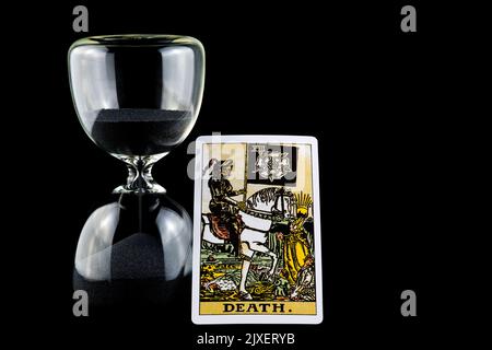 Death tarot card and hourglass isolated against a black background Stock Photo