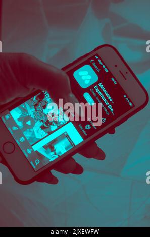 Metaverse Tech Lifestyle Concept - Close-up of a hand holding a mobile phone with metaverse experience app on screen display. Stock Photo