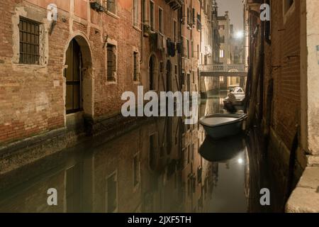 quiet Venetian night with parked boats and lights reflection in city channel Stock Photo