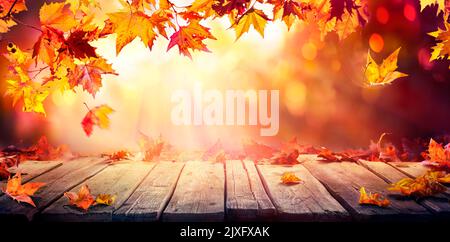 Autumn - Wooden Table With Orange Leaves At Sunset In Defocused Abstract Background Stock Photo