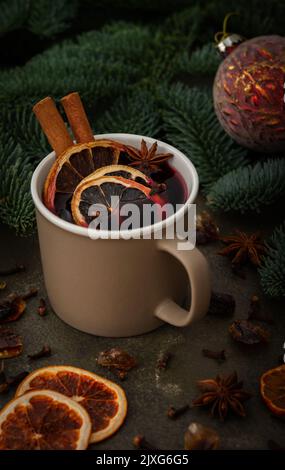 Christmas hot alcoholic drink mulled wine in a mug with citruses, aromatic spices and cinnamon among the spruce branches Stock Photo