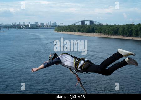 Young man bungee jumping with a view of the river. Safety elements, helmet... Stock Photo