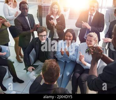 Office employees sit on chairs clap hands greeting presenter or speaker at group meeting close up. Stock Photo