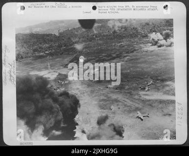 THE DEVASTATING HOLLANDIA ATTACK. These continued attacks ran the total score up to 288 enemy planes destroyed. Huge clouds of smoke and more bombs falling mark the destruction of the Japaneseanese airbase. Stock Photo