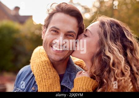 Portrait Of Happy Loving Couple With Woman Giving Man Kiss On The Cheek Stock Photo