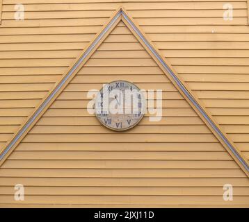 Wooden clock-face on exterior wooden wall with peak detail Stock Photo