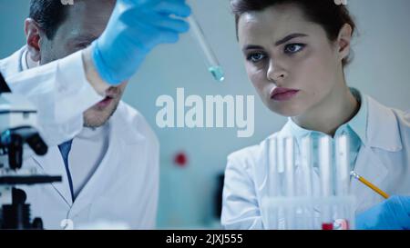 two scientists in white coats looking at test tube with sample in laboratory,stock image Stock Photo