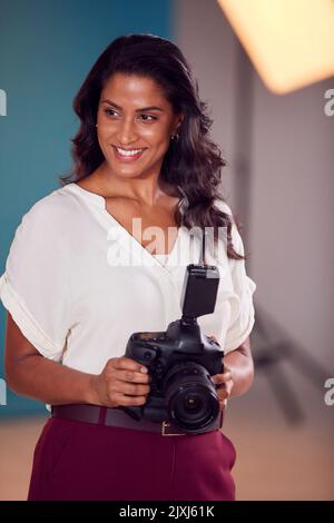 Mature Female Photographer With Camera In Studio For Shoot Stock Photo